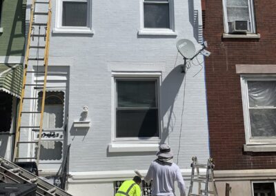 After photo of a Philadelphia, PA brick rowhome facade painted light grey with white window trim and cornice by UMAR Painting Co. exterior painters