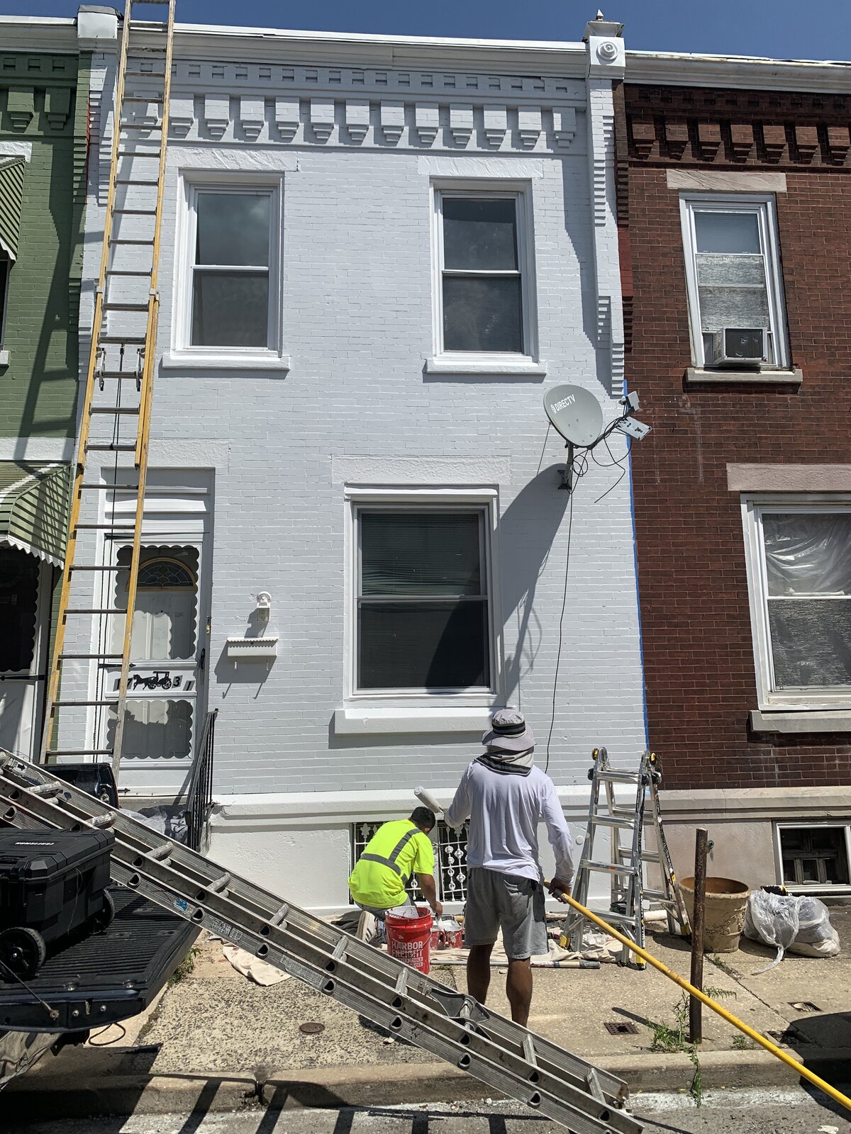 AFTER — Philadelphia Rowhome Brick Painted Light Grey with White Trim | Affordable Philly Painters After photo of a Philadelphia, PA brick rowhome facade painted light grey with white window trim and cornice by UMAR Painting Co. exterior painters
