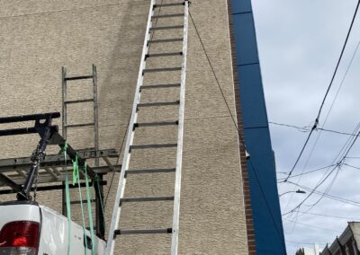 Exterior painting Philadelphia with ladder against tan siding and blue painted trim