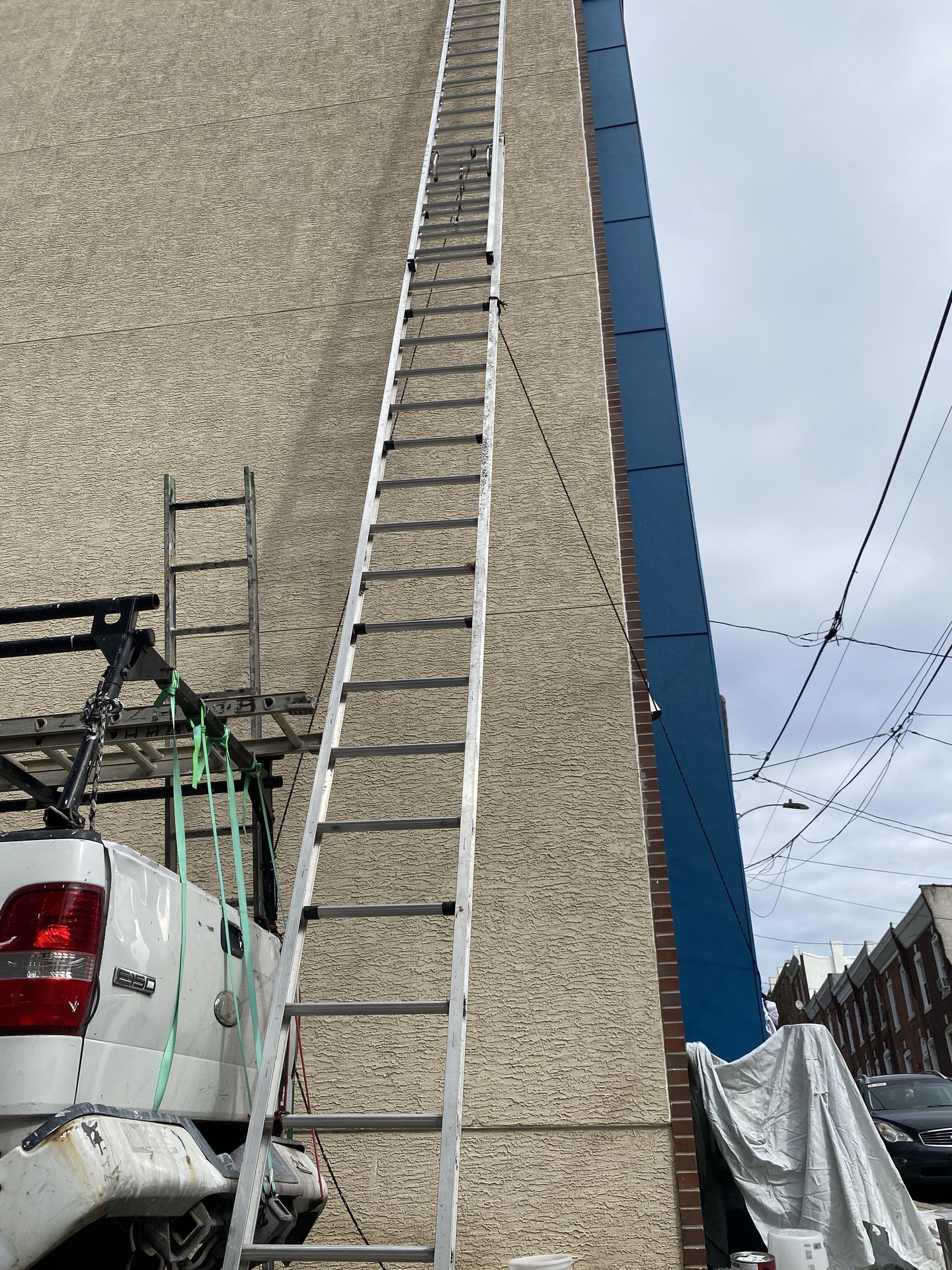 Ladder against tan siding with freshly painted blue trim, Camden County