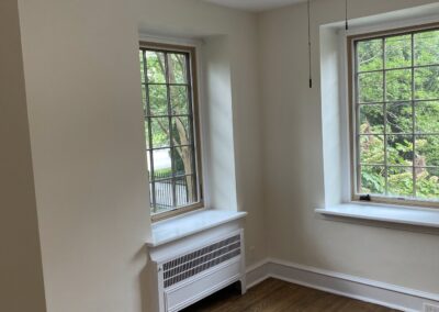 Finished Philadelphia bedroom with light neutral walls, white trim, hardwood floors, and two windows