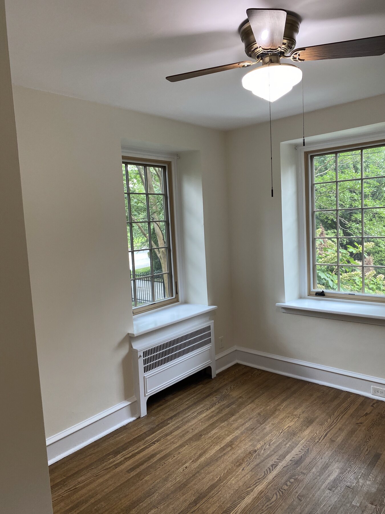 Finished Philadelphia bedroom with light neutral walls, white trim, hardwood floors, and two windows