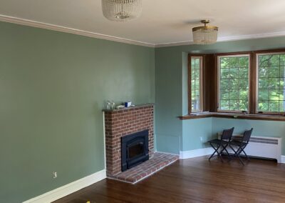 Protected hardwood floor and painting tools in a sage green Philadelphia living room during interior painting