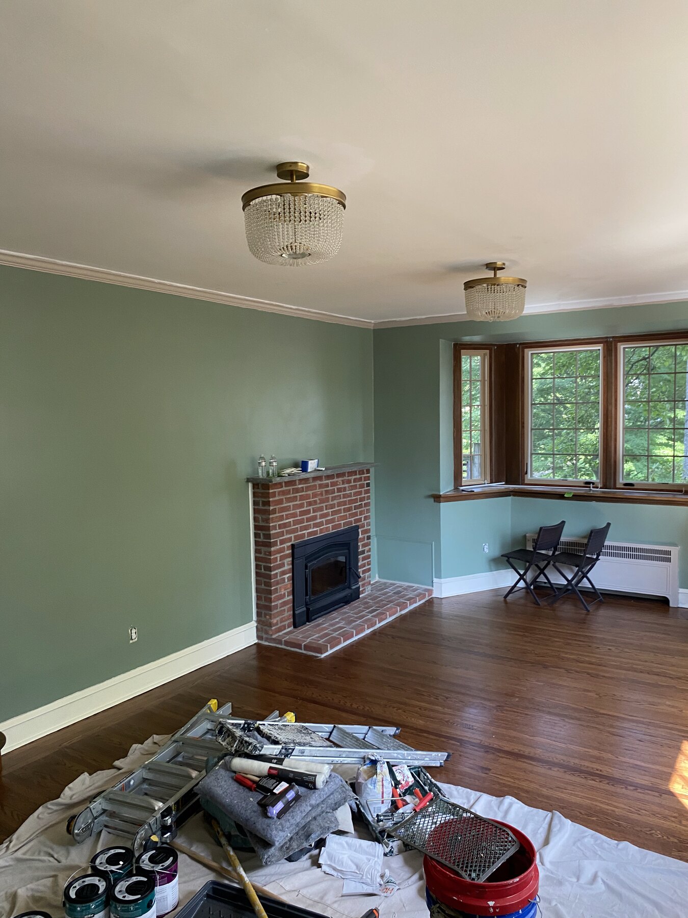 Protected hardwood floor and painting tools in a sage green Philadelphia living room during interior painting