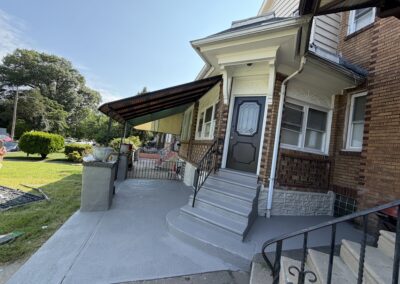 Finished gray porch steps and walkway with white trim on a Philadelphia brick home