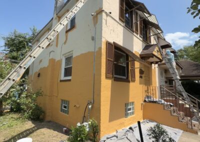Painter and ladders during a two-story Philadelphia stucco exterior repaint