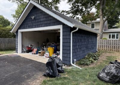 After exterior painting: detached two-car garage repainted deep navy blue with white trim to match the house, in Philadelphia, PA, by UMAR Painting Co.