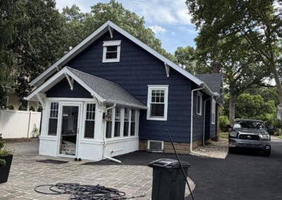 After exterior repaint: side elevation painted deep navy blue with a bright white sunroom, white window trim and clean gutters on a Philadelphia, PA home by UMAR Painting Co.