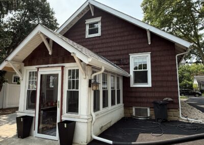 Before exterior repaint: maroon cedar shake side elevation and enclosed sunroom entry of a Philadelphia, PA home, prior to painting by UMAR Painting Co.