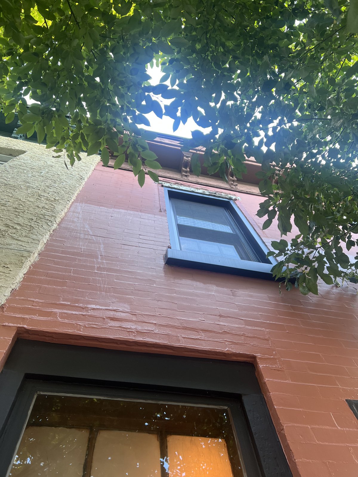 After Exterior Painting - Fresh Terracotta Facade and Black Window Trim, Philadelphia, PA | Affordable Philly Painters After photo looking up a freshly painted terracotta rowhome facade with black window trim and a new white cornice in Philadelphia, PA, painted by UMAR Painting Co.