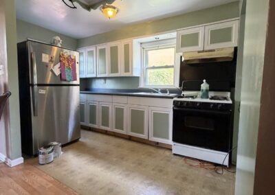 After photo of a repainted kitchen with white cabinets, sage green walls, white trim and refinished hardwood floors in a Philadelphia, PA rental unit, painted by UMAR Painting Co.