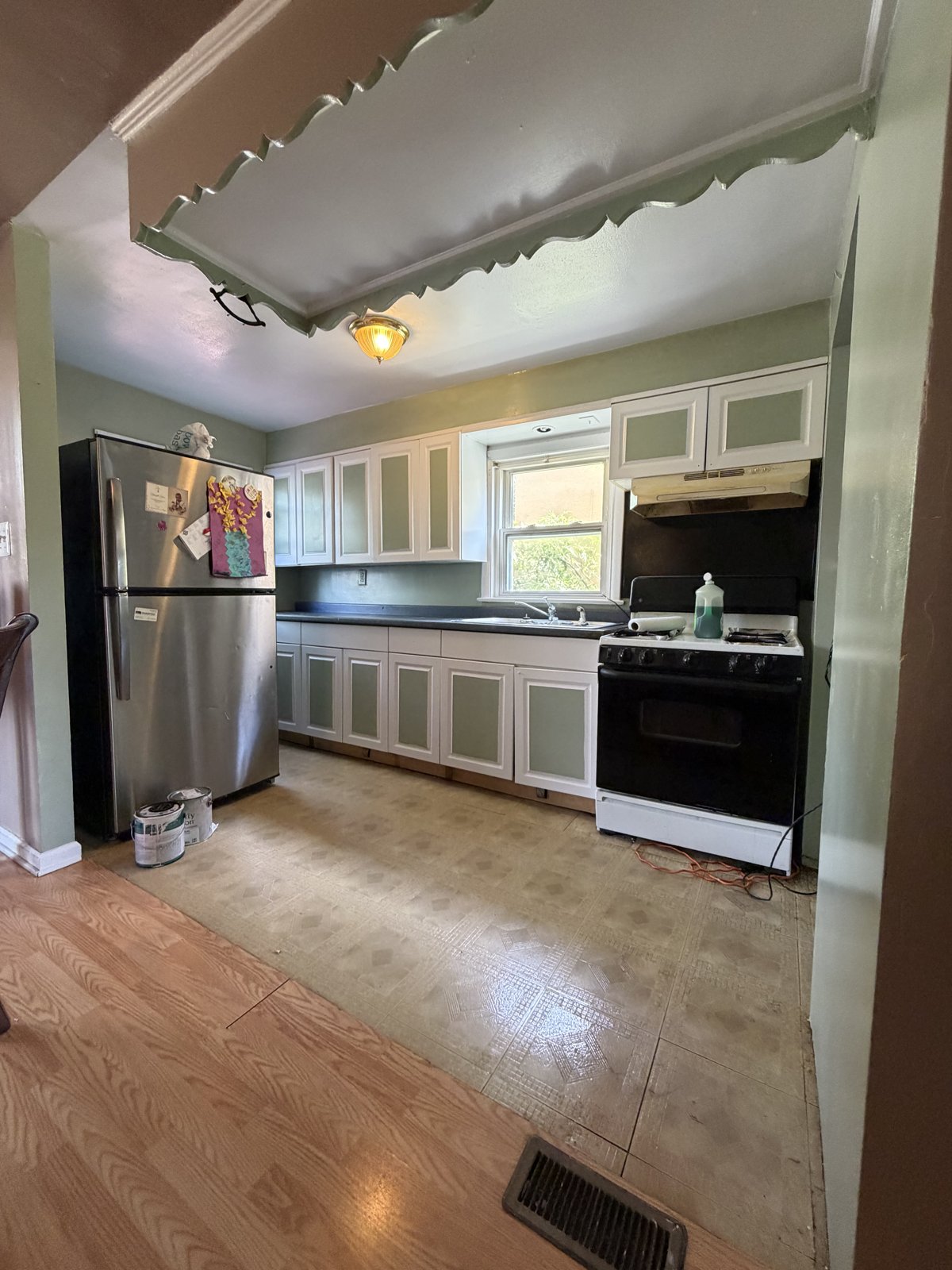 After Kitchen Painting - White Cabinets and Sage Green Walls, Philadelphia, PA | Affordable Philly Painters After photo of a repainted kitchen with white cabinets, sage green walls, white trim and refinished hardwood floors in a Philadelphia, PA rental unit, painted by UMAR Painting Co.