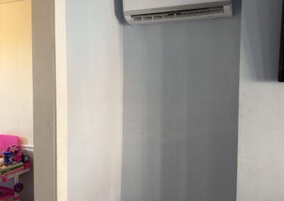After photo of a repaired and freshly painted light blue wall with a wall-mounted mini-split and white trim in a Philadelphia, PA home, completed by UMAR Painting Co.