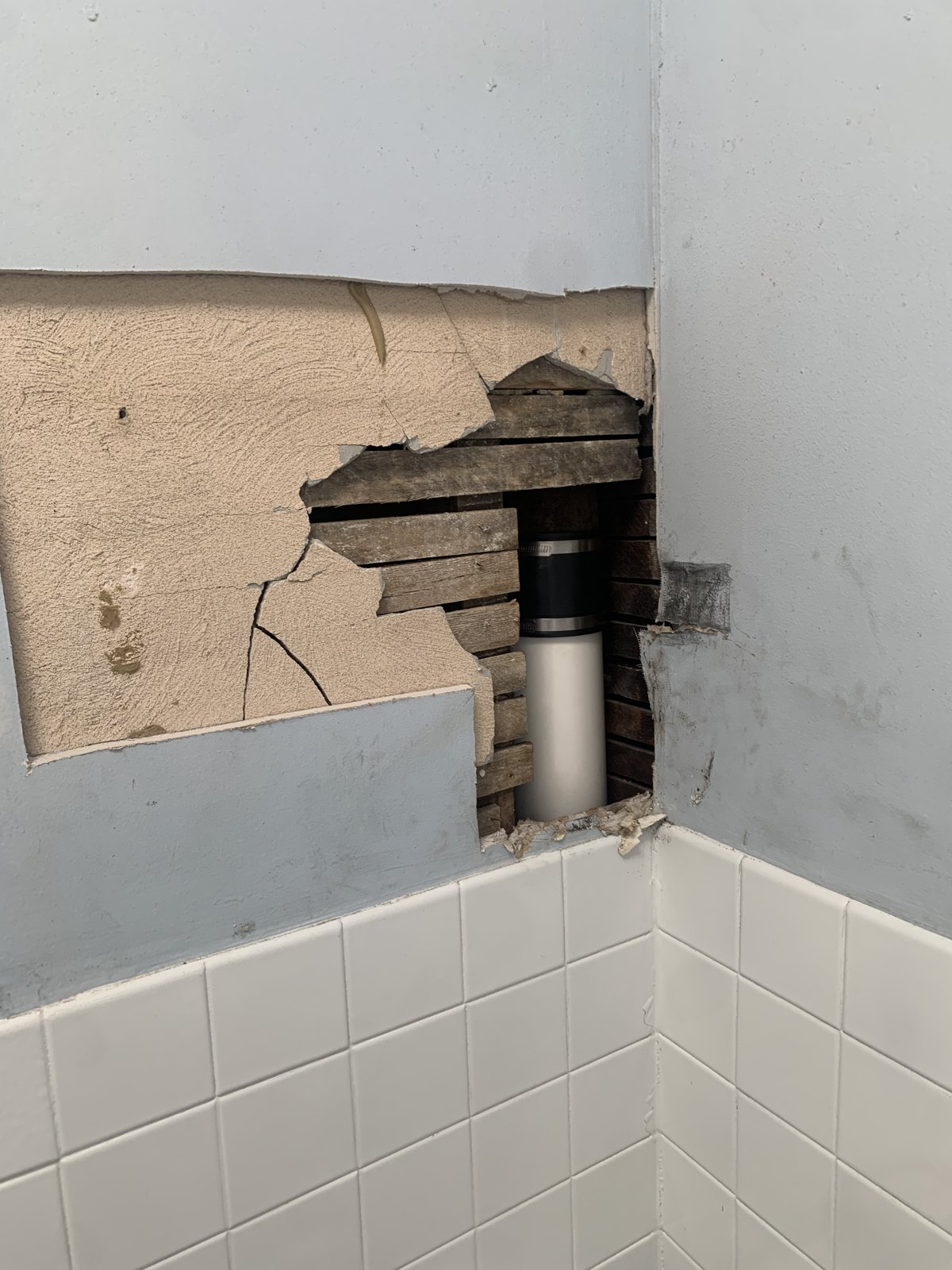 Before Bathroom Ceiling Repair - Plaster Hole Above Tile Shower, Philadelphia, PA | Affordable Philly Painters Before photo of a hole cut in a plaster bathroom ceiling above white tile to access a drain pipe in a Philadelphia, PA rowhome, before drywall patching and painting by UMAR Painting Co.