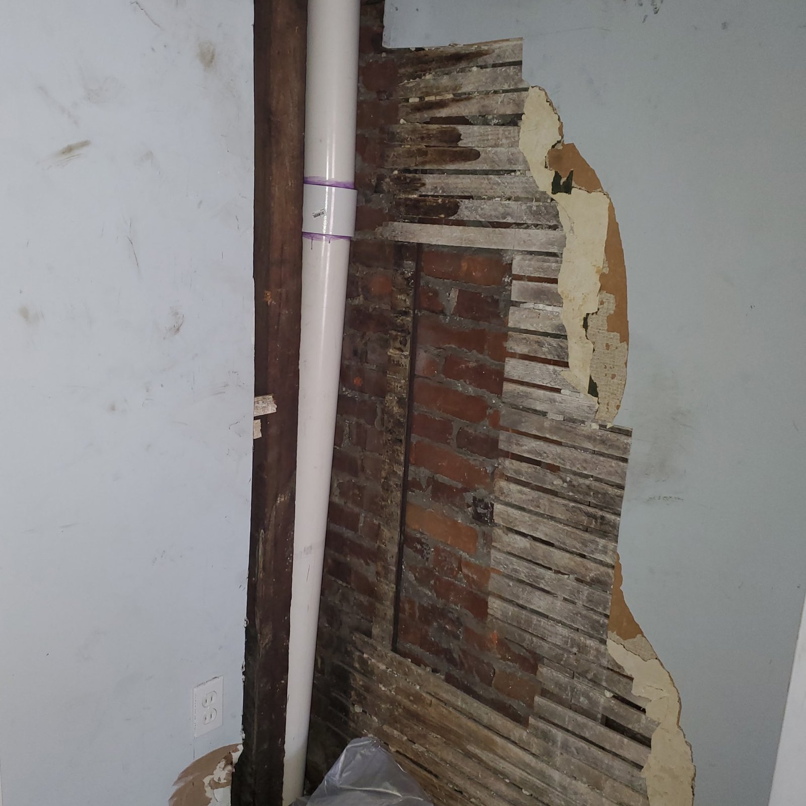 Before Plaster Repair - Failed Plaster and Lath Exposing Brick Party Wall, Philadelphia, PA | Affordable Philly Painters Before photo of failed plaster and wood lath exposing the brick party wall and a new PVC drain line in a Philadelphia, PA rowhome, prior to plaster repair and repainting by UMAR Painting Co.