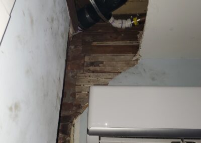 Before photo of damaged plaster with exposed wood lath, brick and cast iron pipe above a wall-mounted mini-split unit in a Philadelphia, PA home, before drywall repair and painting by UMAR Painting Co.
