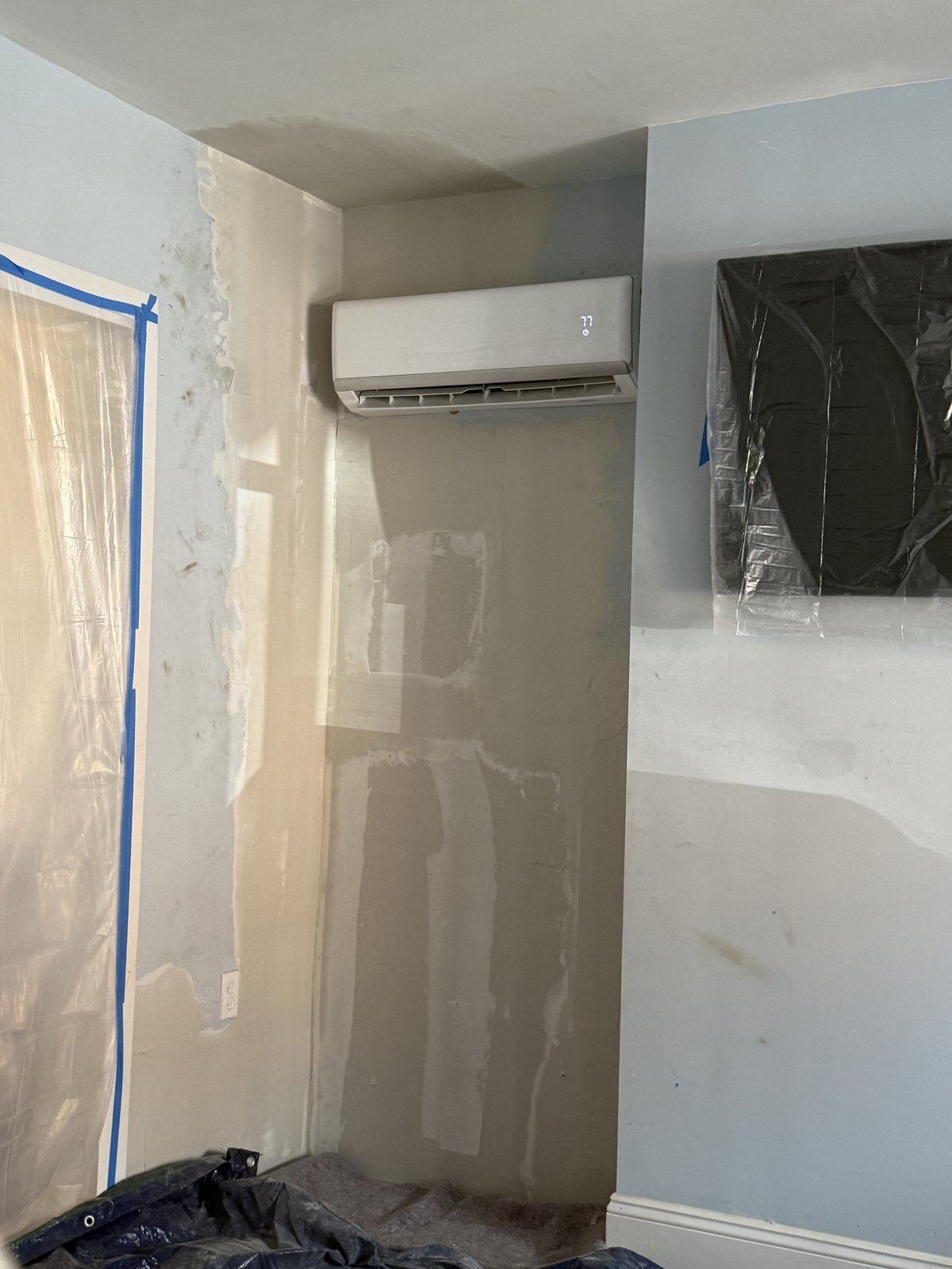 During Repair - Skim Coated Wall Around Mini-Split Before Paint, Philadelphia, PA | Affordable Philly Painters In-progress photo of a skim coated and sanded drywall repair around a wall-mounted mini-split in a Philadelphia, PA home, masked and ready for primer and paint by UMAR Painting Co.
