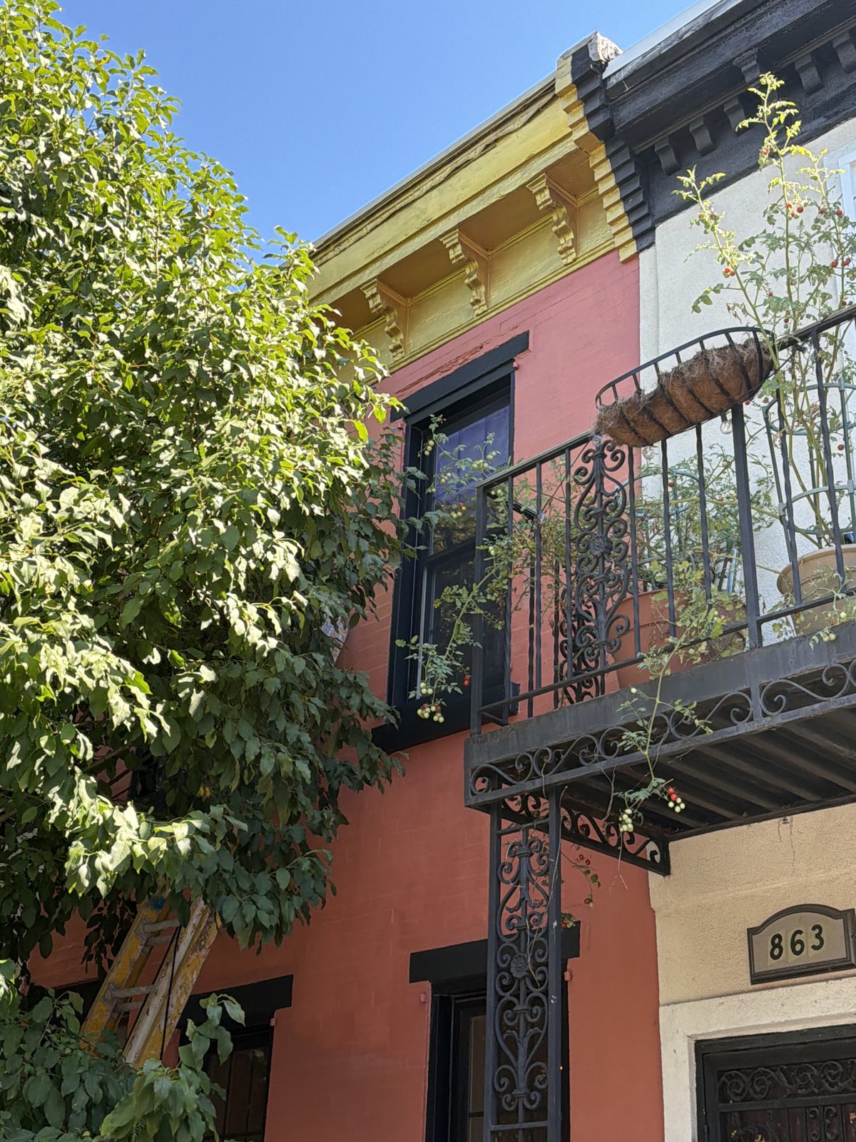 Exterior Rowhome Facade Repaint - Terracotta Stucco with Black Trim and Ironwork, Philadelphia, PA | Affordable Philly Painters Exterior painting of a Philadelphia, PA rowhome facade in terracotta with black window trim, black wrought iron balcony and gold cornice details by UMAR Painting Co. exterior painters